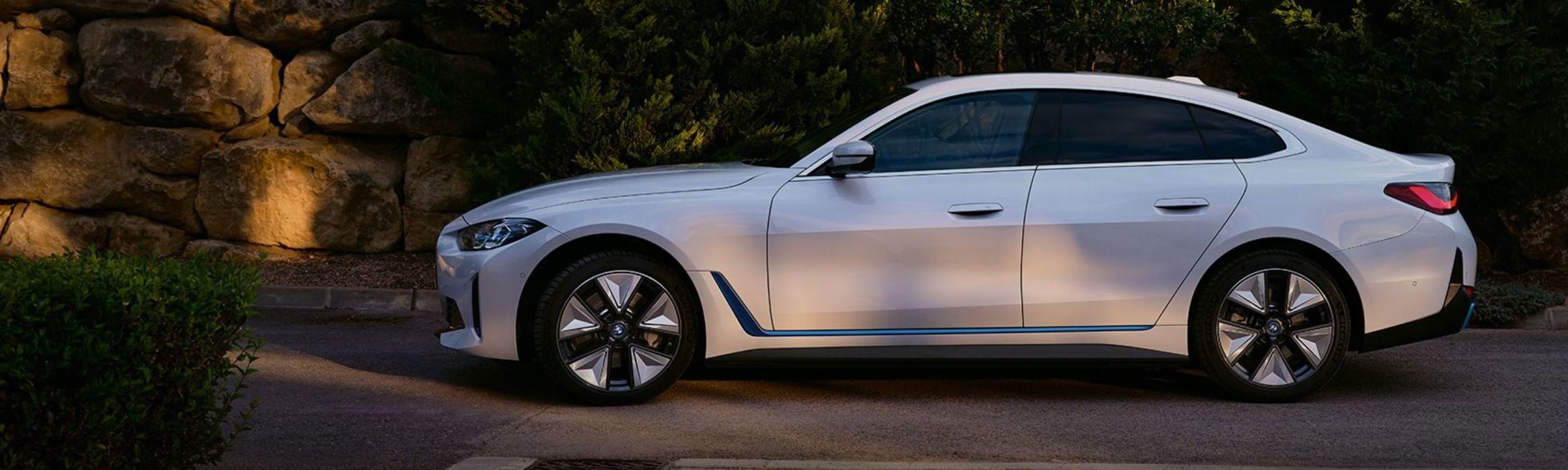 A BMW car parked in front of a hedge and wall